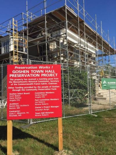 Goshen's town hall, covered in scaffolding and mid rehabilitation. A large red sign in front of this CPA project site reads "Preservation Works! Goshen Town Hall Preservation Project"